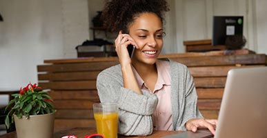 Young woman talking on cell phone using on a laptop