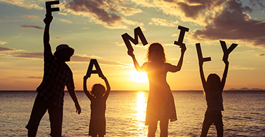 Family holding word FAMILY at sunset