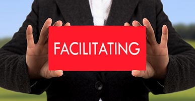 man holding card that says facilitating