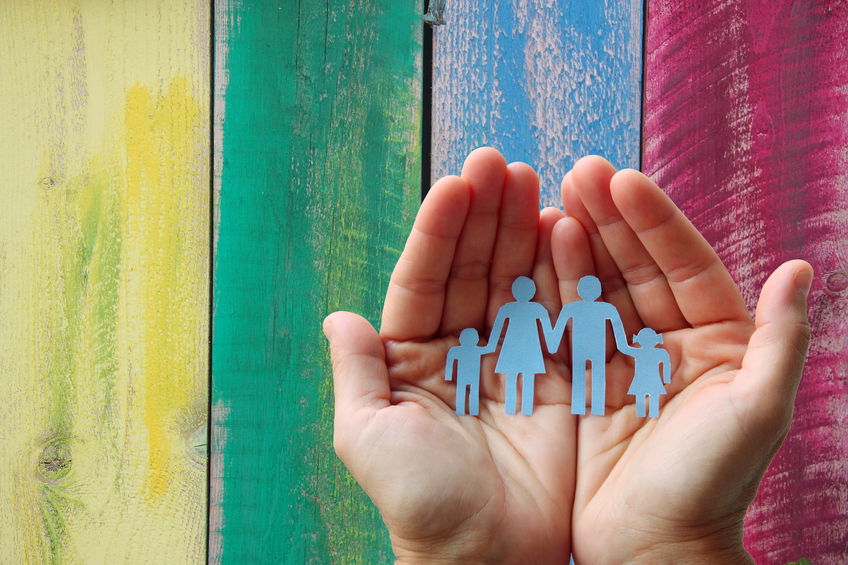 Hands holding paper cut-out of a family