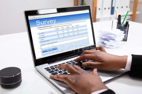 image of two hands typing on a laptop that screen reads Survey.