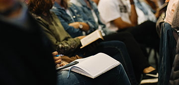 People writing on notebooks in audience