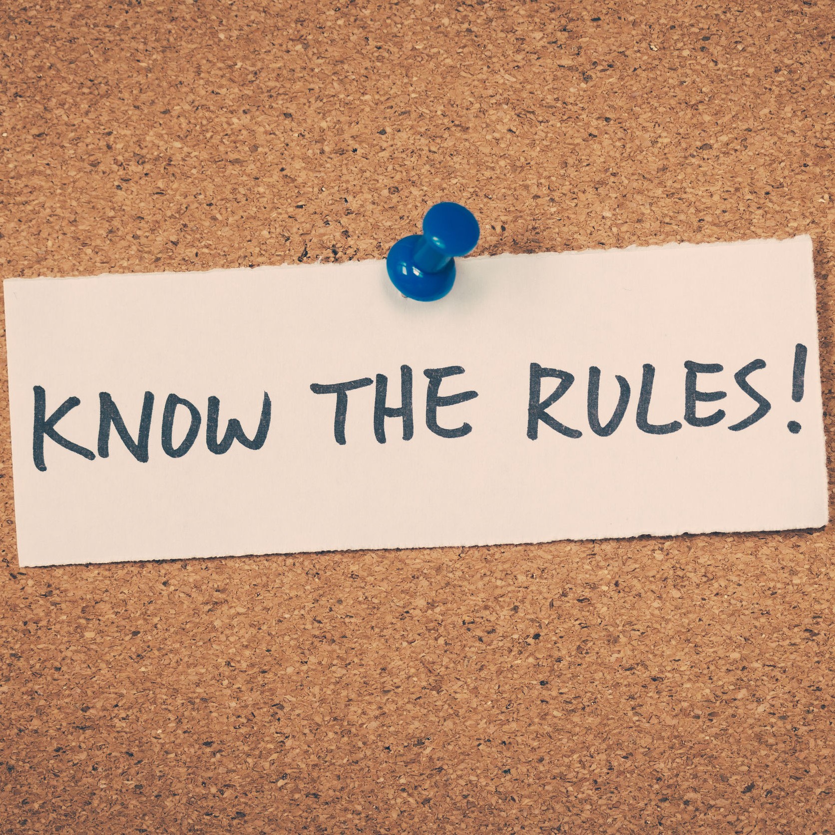 Cork board with green tac and note that says "Know the rules!"