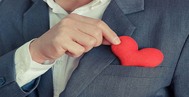 Man in suit pulling heart out of front pocket