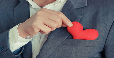 man putting heart in front coat pocket